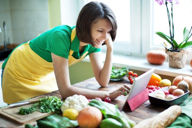Woman in Yellow Apron at Counter Searches What is FODMAP Before Following Diet Plan | Vitacost.com/blog