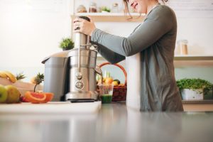Woman Carefully Using Juicer in Kitchen to Keep for Long-Term Use | Vitacost.com/Blog