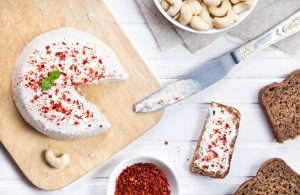 Hard Cashew Cheese on Cutting Board with Knife and Slices of Bread
