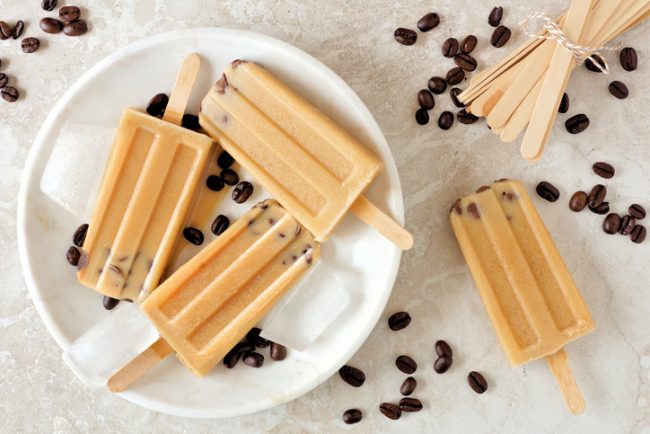 Vegan Coffee Ice Pops with Protein Powder Coffee Ice Pops on White Plate with Coffee Beans Scattered Around | Vitacost.com/blog