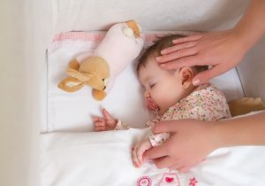 Mother Checking on Sleeping Infant in Crib During Baby Safety Month | Vitacost.com/blog