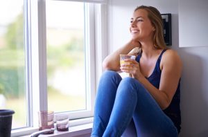 Smiling Woman Looking out Window Thinking About Vitamins for Vegans | Vitacost.com/blog