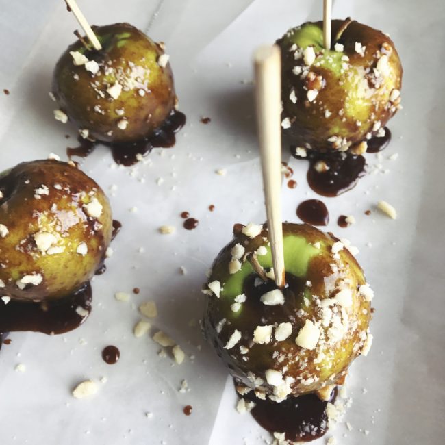 Caramel Apples with 2-Ingredient Caramel Recipe  4 Caramel Apples with Crushed Macadamia Nuts on White Parchment Paper #recipe| Vitacost.com/blog