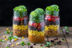 3 Servings of Mason Jar Taco Salad on Wood Table with Corn, Beans & Cilantro | Vitacost.com/blog