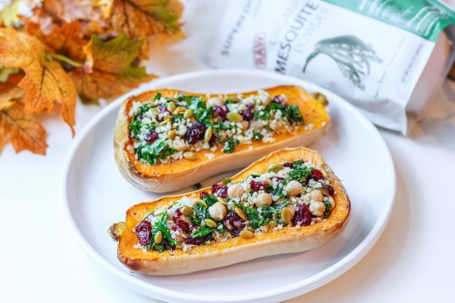 Stuffed Butternut Squash with Quinoa, Kale, Chickpeas & Cranberries on White Plate with Fall Leaves #recipe | Vitacost.com/blog