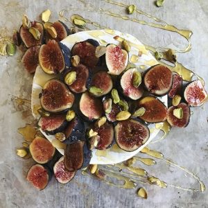 White Plate Full of Baked Brie, Covered in Fresh Fig Slices, Honey & Pistachios | Vitacost.com/blog