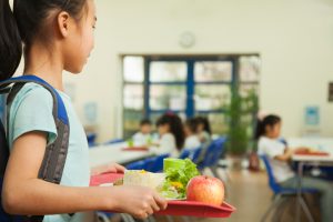 Female Middle School Student in Cafeteria Holding Tray with Vegetarian Lunch | Vitacost.com/Blog