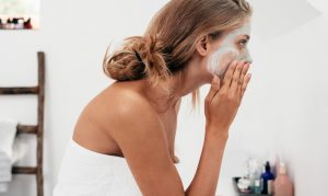 Young woman applying a white at-home face mask