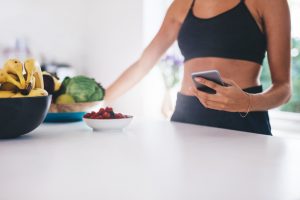 Fit woman in kitchen thinking about skipping breakfast