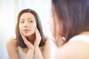 Brunette Woman Checking Her Skin for Stress Breakouts in the Mirror | Vitacost.com/blog