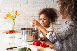 Mother Teaching Healthy Eating Habits to Child While Cutting Vegetables for Soup | Vitacost.com/blog