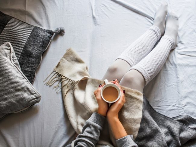 Woman Wearing Cozy Socks and Drinking Tea to Relieve Stress | Vitacost.com/blog