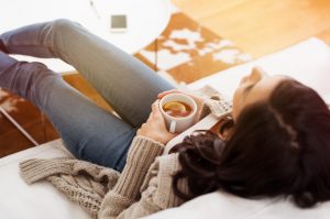 Woman Lying on Couch Drinking Tea to Relive Stress | Vitacost.com/blog