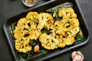 Two Whole Roasted Cauliflower Heads with Garlic in Pan | Vitacost.com/blog