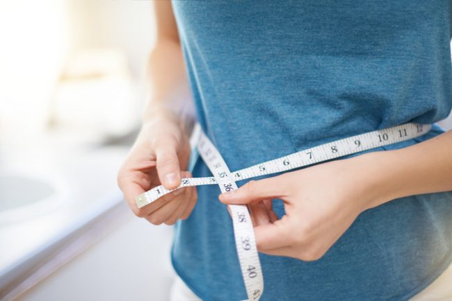 Woman Measuring Her Waist Because She's Trying to Lose Weight | Vitacost.com/blog