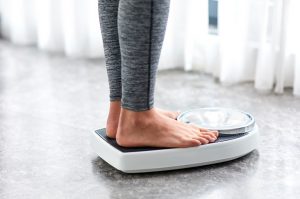 Woman Following Keto Diet Standing on Scale in Gray Leggings | Vitacost/com/blog