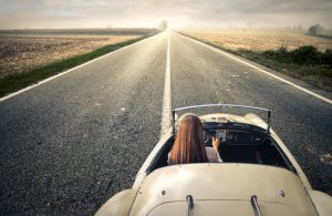 Woman Driving Convertible on Long Open Road Trying to Stay Healthy in the Car | Vitacost.com/blog