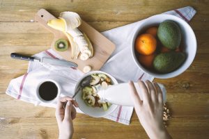 Examples of Enzymes in Food are Shown in This Breakfast: Hand Pours Kefir Over Bowl of Bananas, Kiwi & Granola | Vitacost.com/blog