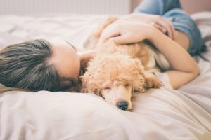 A Woman Cuddling with Her Dog in Bed | Vitacost.com/blog
