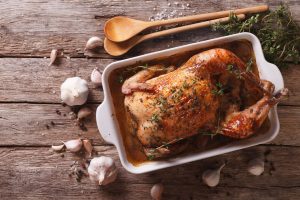 Tips for How to Brine to Get a Juicy, Cooked Turkey in Roasting Pan on Wood Table with Wood Spoons | Vitacost.com/blog