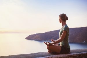 A Woman with New Year Goals Meditates Overlooking the Ocean, Uses Supplements to Support Her Health | Vitacost.com/blog
