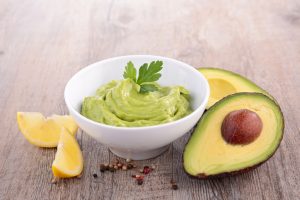 Bowl of Avocado Dressing Alongside an Open Avocado & Lemon Wedges | Vitacost.com/blog