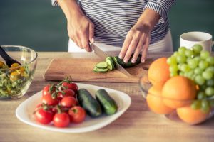Woman in the Kitchen Slicing Vegetables to Make Meal to Satisfy Plant-Based Diet Goals | Vitacost.com/Blog