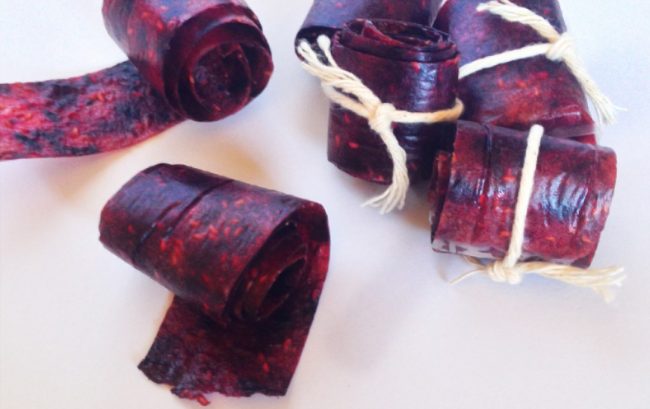 Several Red Roll-Ups of Fruit Leather Snacks for Kids on White Counter #recipe | Vitacost.com/blog