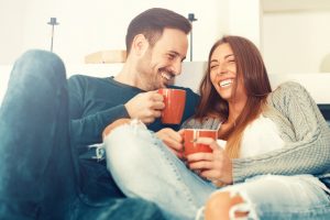 Couple Trying to Reduce Stress for Heart Health by Relaxing and Laughing on Couch | Vitacost.com/blog