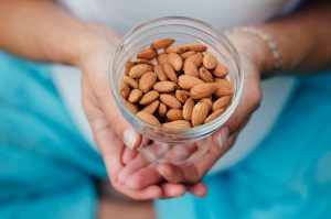 Woman Holding Jar of Almonds for Health Benefits of Healthy Fats | Vitacost.com/blog