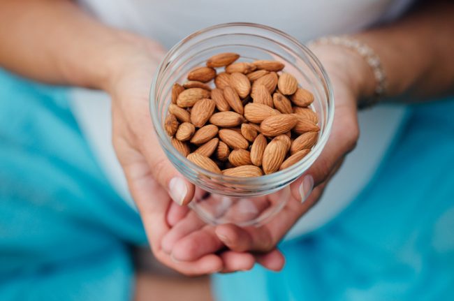 Woman Holding Jar of Almonds for Health Benefits of Healthy Fats  | Vitacost.com/blog