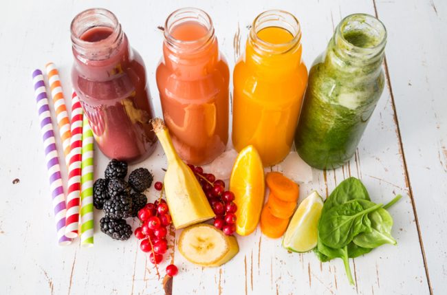 Bottles of Colorful Fruit & Vegetable Juice Drinks in a Row on a White Wooden Table | Vitacost.com/blog