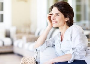 Middle-Aged Woman Sitting on Couch Contemplating a Hormone Balancing Diet | Vitacost.com/blog