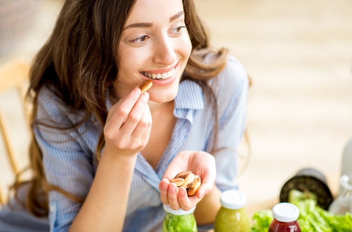 Woman Concerned About Nutrient Absorption Eating Handful of Almonds | Vitacost.com/blog