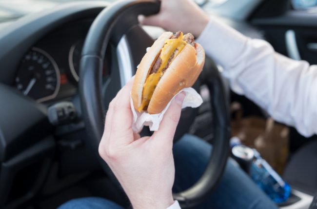 Man at Risk for Immune Health Problems Eating Junk Food Burger in Car | Vitacost.com/blog