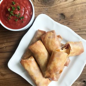A Plate of Pizza Egg Rolls with a White Ramekin Filled with Tomato Dipping Sauce #recipe | Vitacost.com/blog