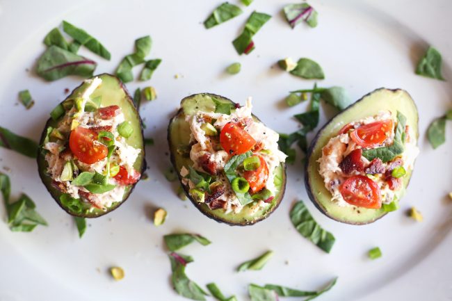 3 Stuffed Avocado BLT Halves on White Platter, Topped with Tomatoes & Green Onion #recipe | Vitacost.com/blog