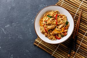 Asian Sesame Chicken Pad Thai with Peppers & Carrots on Slate Counter with Bamboo Placemat & Chopsticks #recipe | Vitacost.com/blog