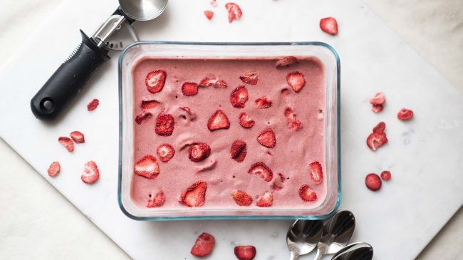 Homemade Vegan Strawberry Ice Cream (Banana-Free, Dairy-Free & Grain-Free) Glass Baking Dish With Homemade Vegan Strawberry Ice Cream & Dried Strawberries on Top #recipe | Vitacost.com/blog
