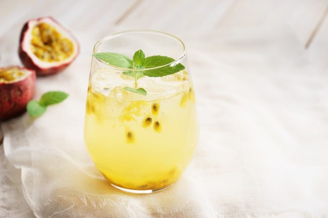 Passion Fruit Iced Tea Beauty Drink Recipe One Serving of Passion Fruit Iced Tea Beauty Drink with Collagen & Mint Leaves on Wood Counter #recipe | Vitacost.com/blog