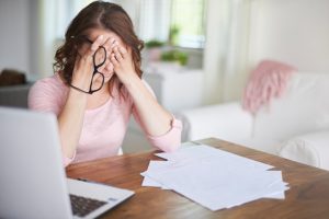 Woman at Desk Holding Head in Pain from Side Effects of Stress | Vitacost.com/blog