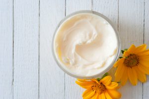 Bowl of Creamy DIY Body Butter on Wooden Surface with Yellow Flowers | Vitacost.com/blog