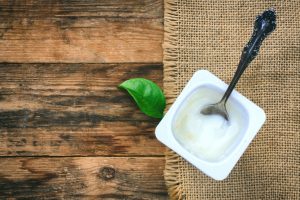 Above View of Spoon in Open Container of Yogurt on Wooden Table with Burlap Placemat | Vitacost.com/blog