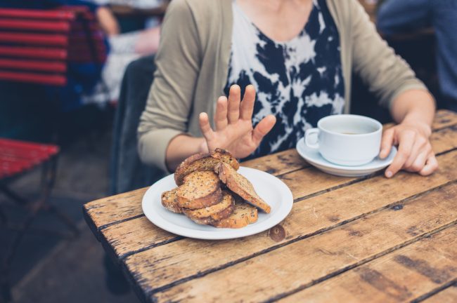 5 Surprising Foods that Contain Gluten Woman Pushing Away Plate of Gluten-Containing Foods | Vitacost.com/Blog