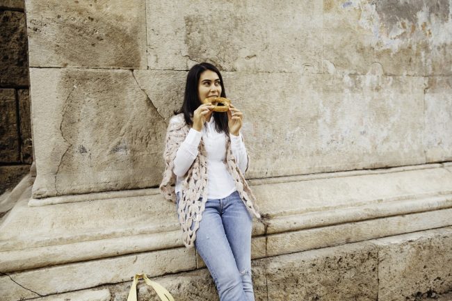 Dark-Haired Woman Eats a Bagel & Wonders How to Speed Up Metabolism | Vitacost.com/blog