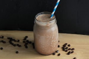 Macadamia Nut Cold Brew Smoothie in Jar with Straw and Surrounded by Coffee Beans | Vitacost Blog