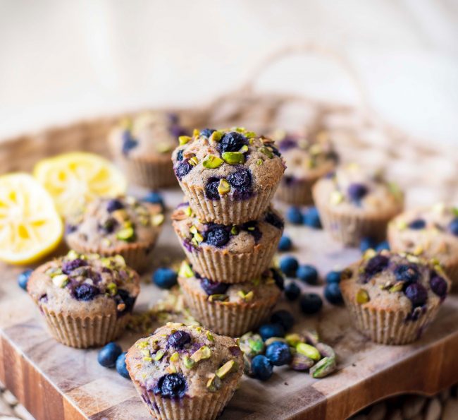 Lemon Blueberry Muffins With Pistachio Crumb Topping Stacked on Wood Cutting Board #recipe | Vitacost.com/blog