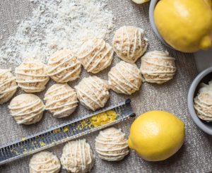 12 Lemon Coconut Macroons Lined Up With Lemon Zest, Lemons & Shredded Coconut #recipe | Vitacost.com/blog