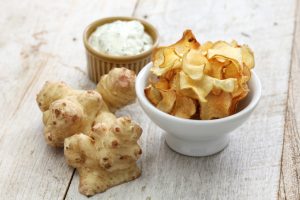 Sunchoke Chips in Bowl Next to Sunchokes on Wood Background | Vitacost Blog