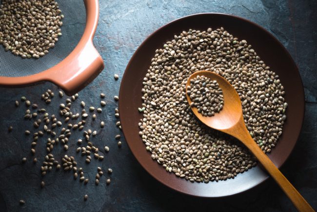 Shallow Brown Wooden Bowl and Spoon Filled with Hemp Seeds on Slate Gray Table | Vitacost.com/blog